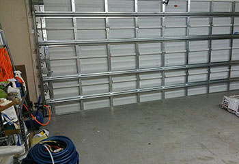 Close-up of dented and misaligned steel garage door panel before repair in Brooklyn Park
